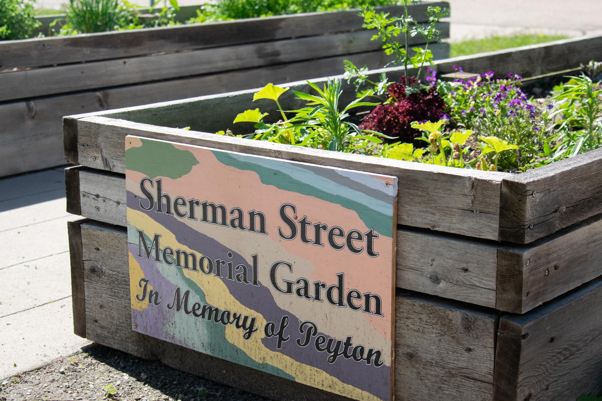 Front garden boxes at Wellness Center. Sign reads: Sherman Street Memorial Garden In Memory of Peyton.