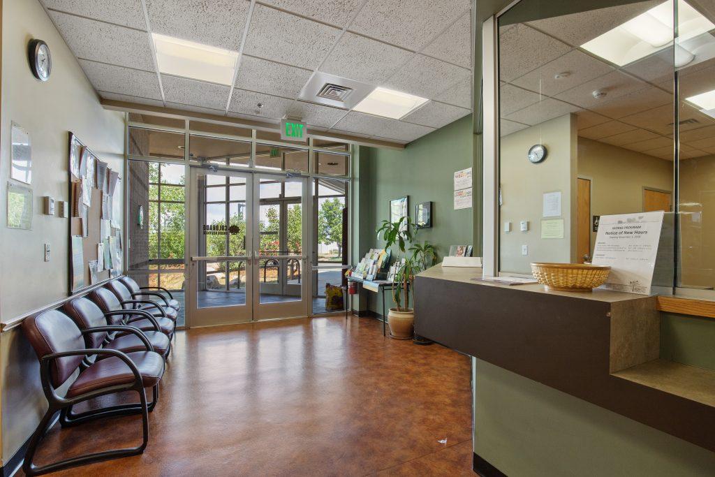 Crisis Center waiting room. Green painted walls with row of red chairs and large glass doors.