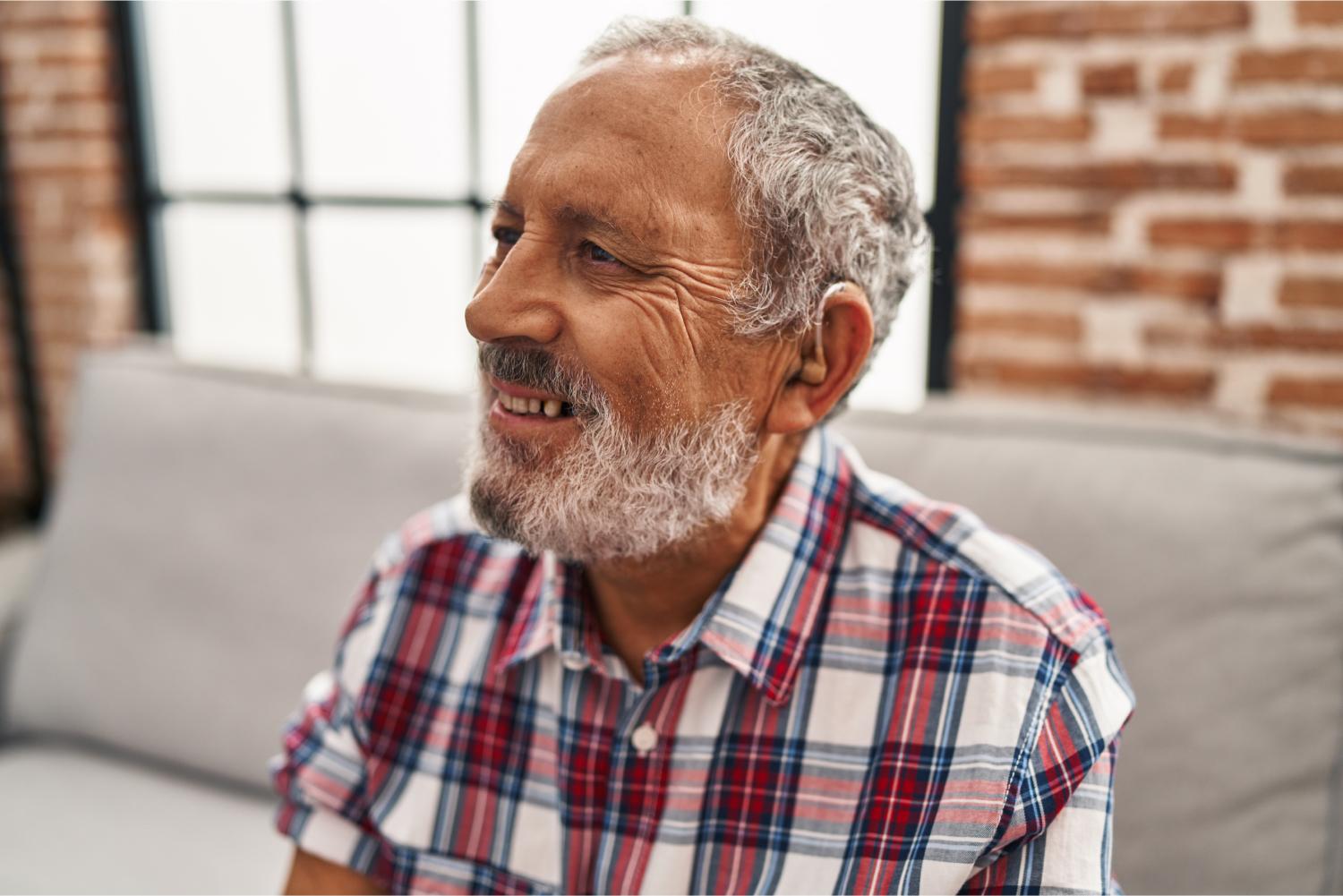 Man using hearing aid sitting on sofa.