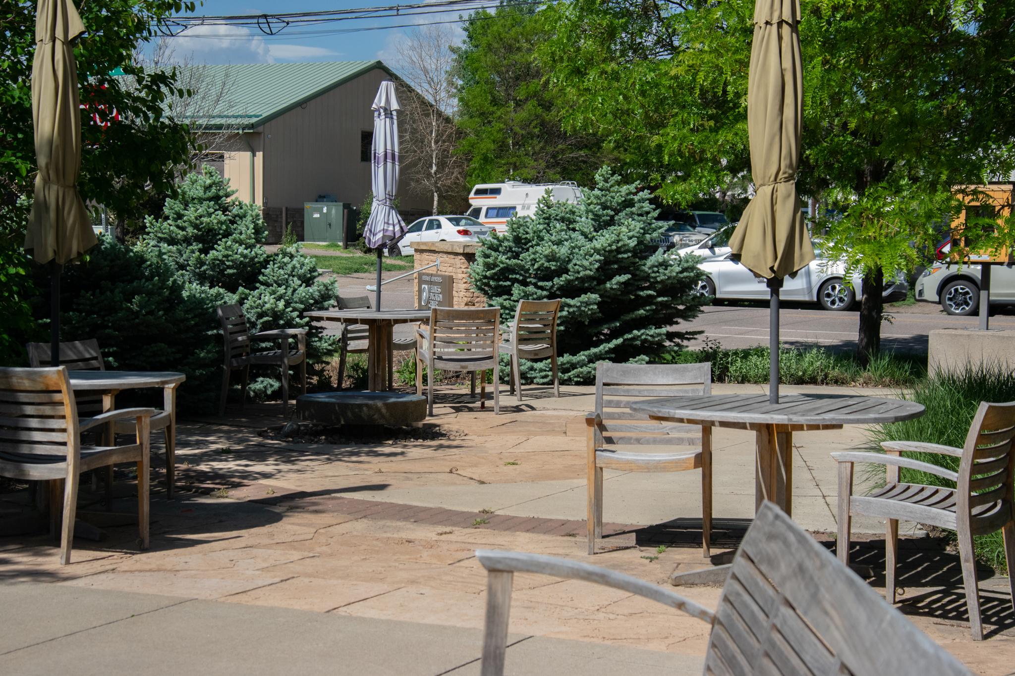 Patio at wellness center. Patio tables, chairs, and closed umbrellas.