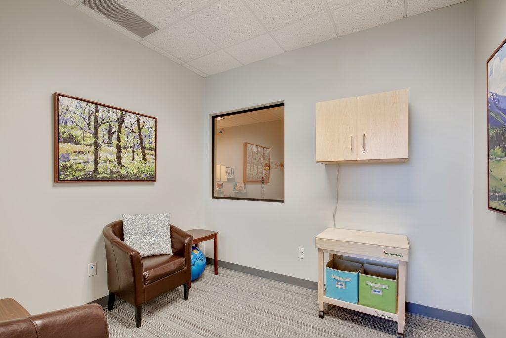 Office with brown leather chairs, window, nature murals, wall-hung cabinet, and small wooden table.