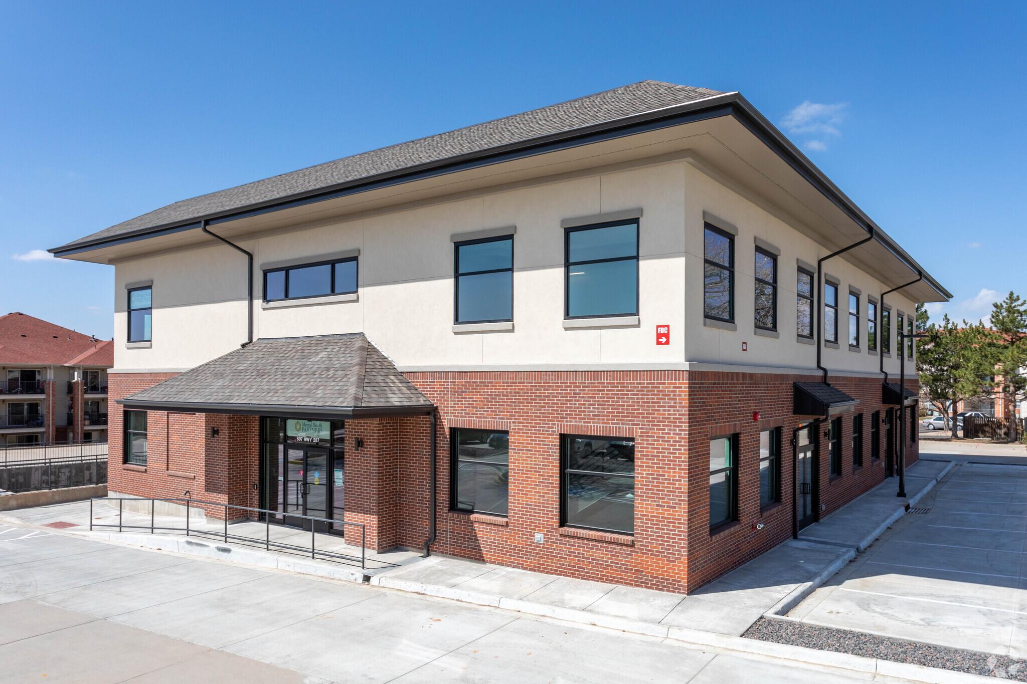 Broomfield Office Outside: square building with red brick first floor and cream stucco second floor. 