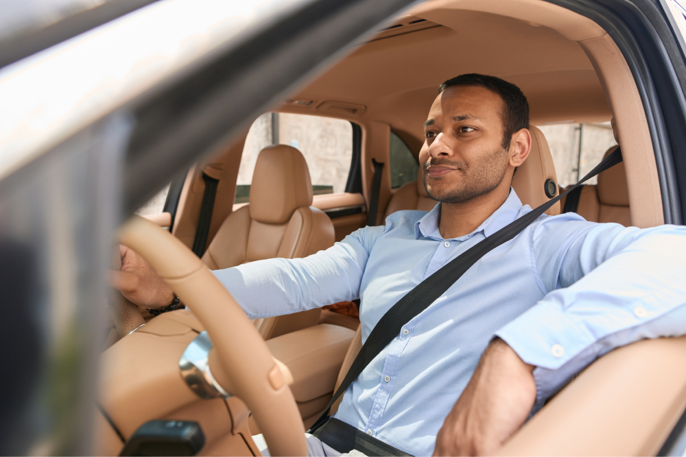 Man driving in car with arm leaning out window.