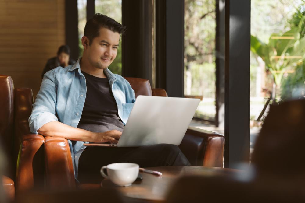 Withdrawal Management Tile: Person sitting on chair working on laptop.