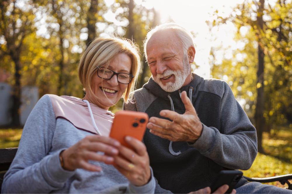 Cognitive Enhancement Therapy (cet) Tile: Two adults sitting on park bench looking at phone.