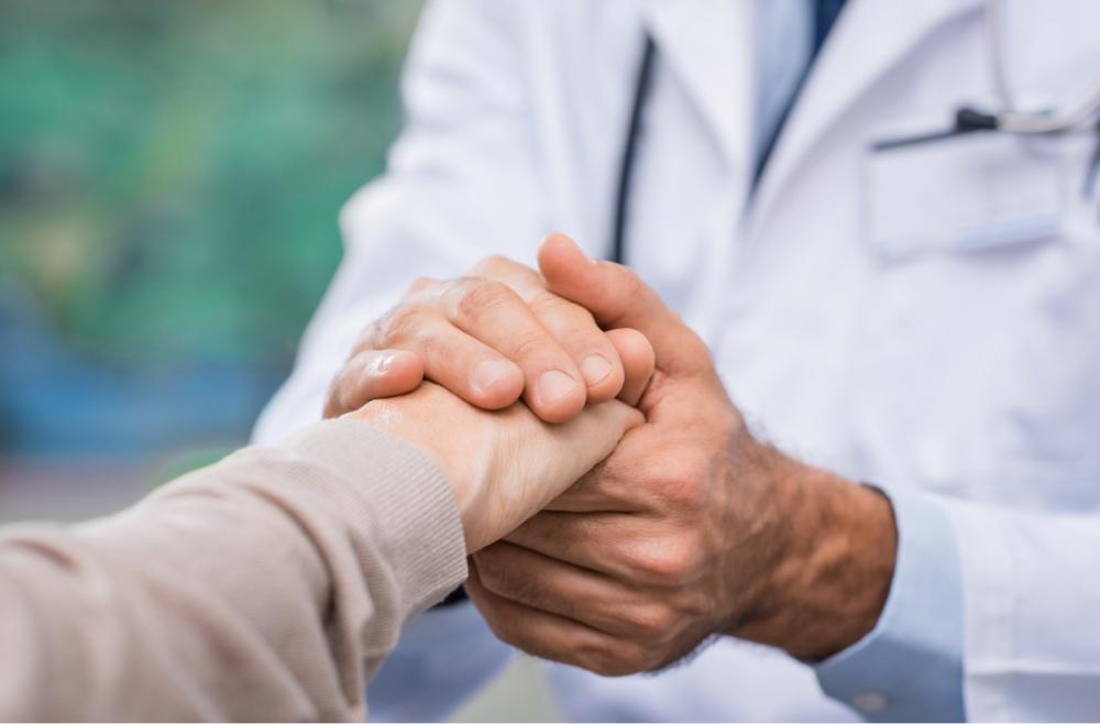 Crisis Services Tile: Person in white coat holding hand on patient.