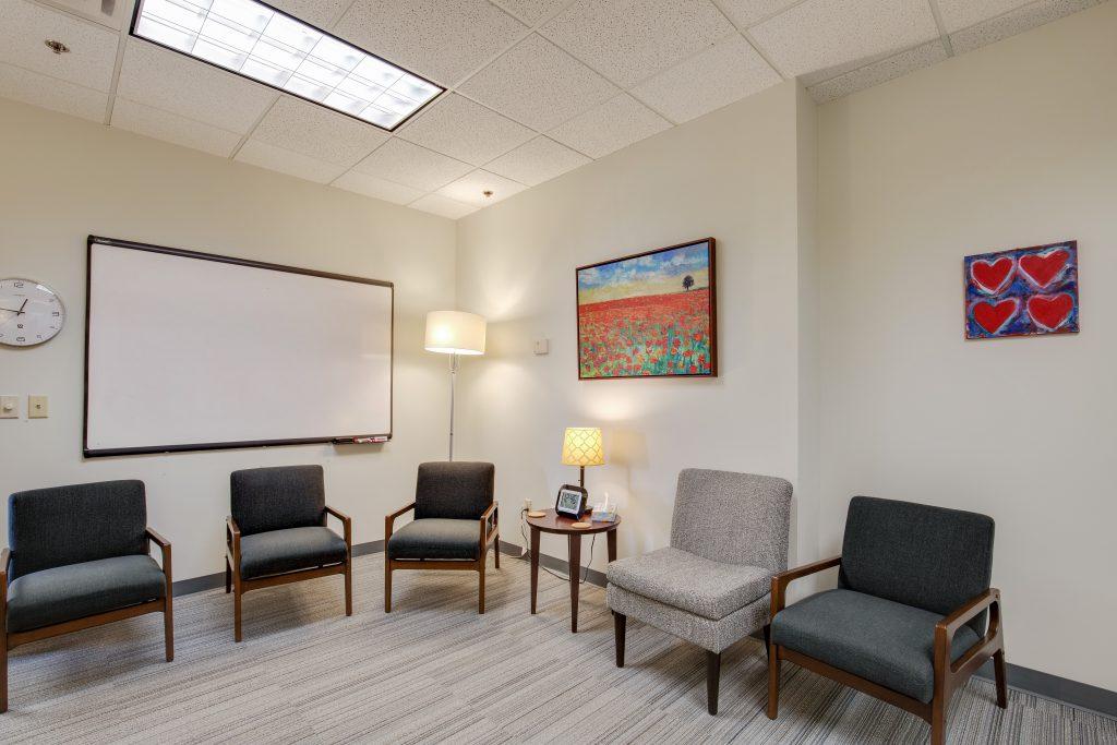 Group meeting room with circle of chairs, whiteboard, and colorful red art.