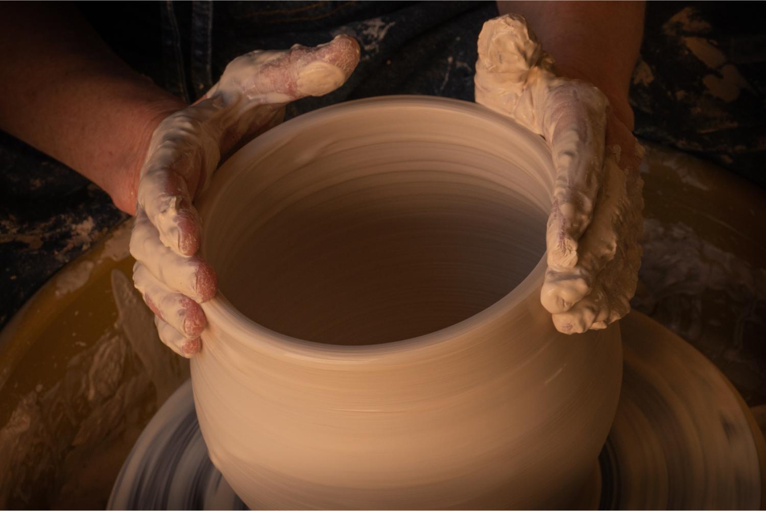 Hands molding a clay pot.