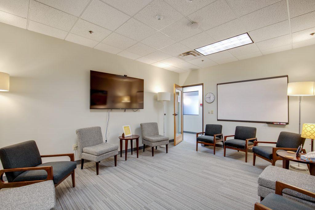 Group meeting room with circle of chairs, whiteboard, and tv screen.