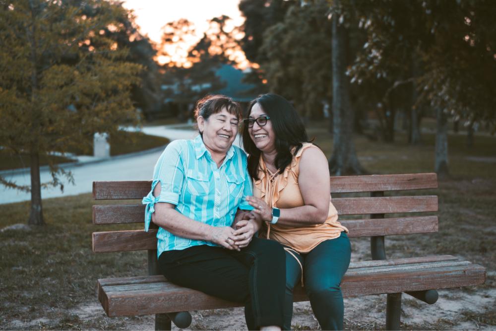 Integrated Health Home Tile: Two women sitting on bench laughing.