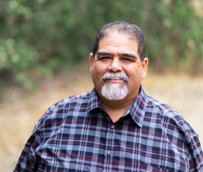 Man Smiling at Camera in Field.