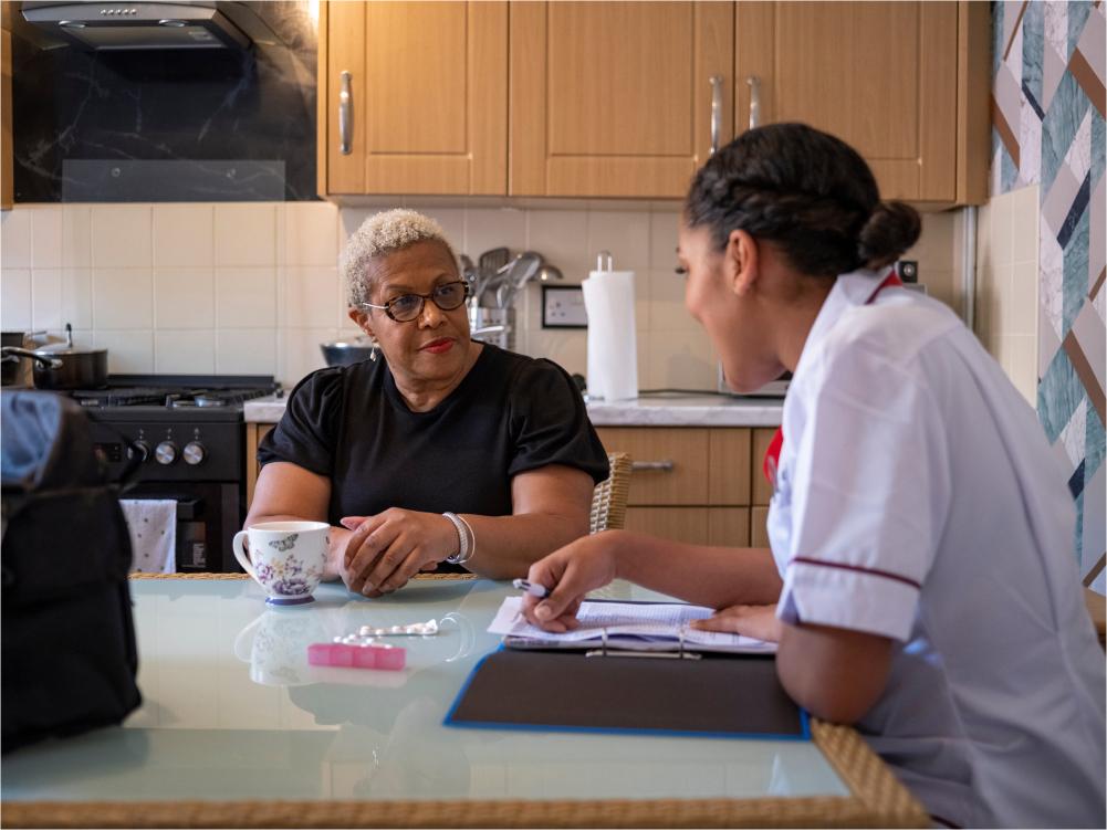 Clinician talking to client at kitchen table.