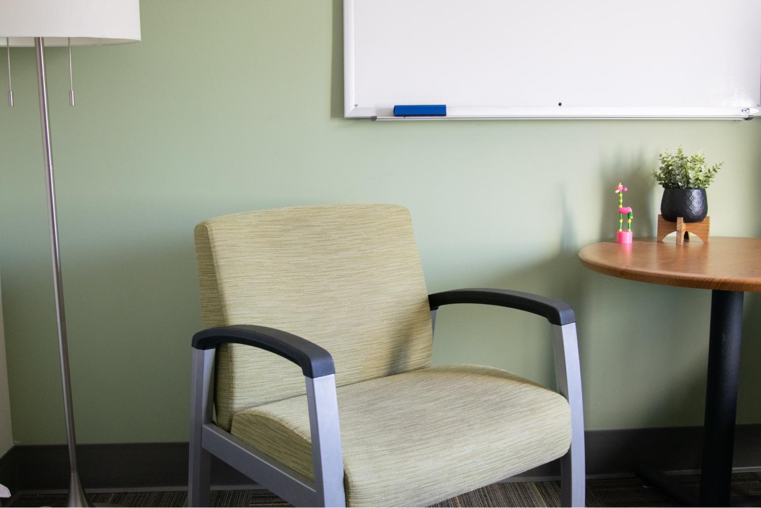 Green chair sitting in between a lamp and side table.