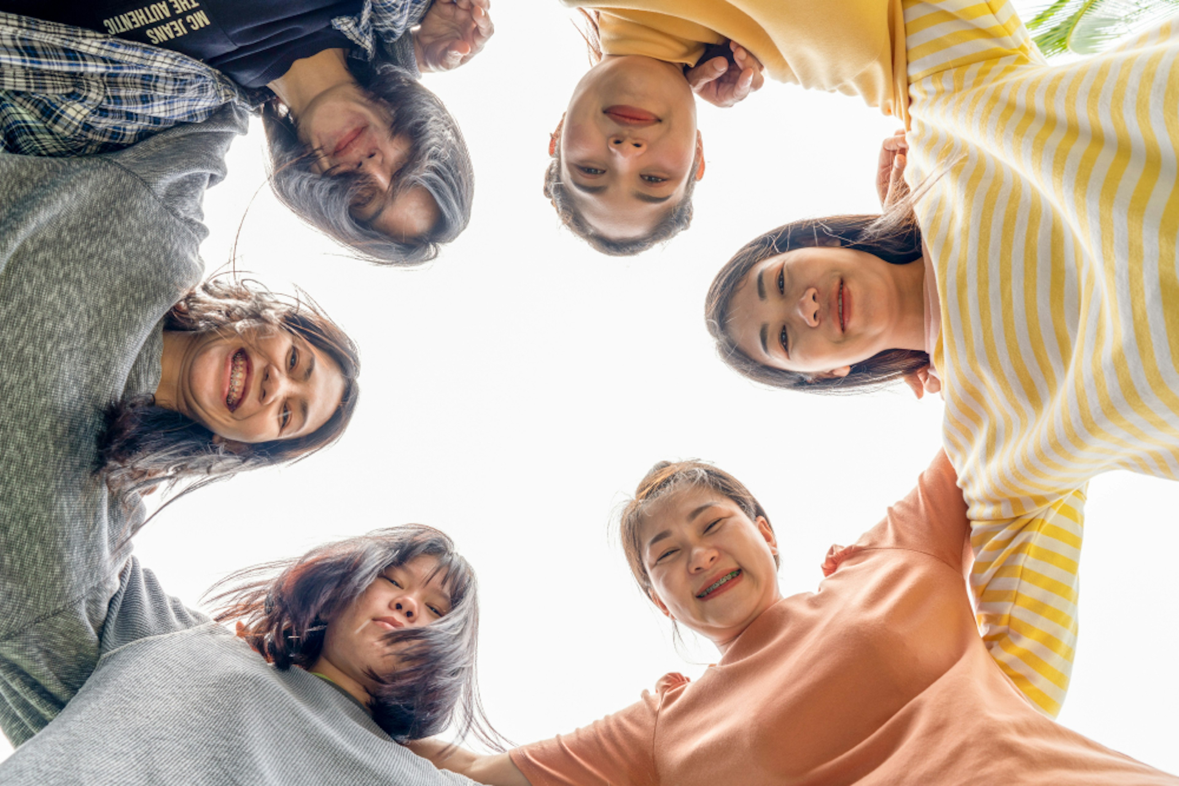 Teens in a circle with hands on shoulders looking down at the camera